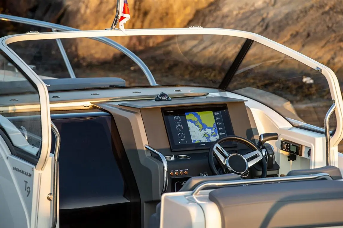 Interior view of a modern boat's dashboard, featuring a navigation screen, steering wheel, and control panel.